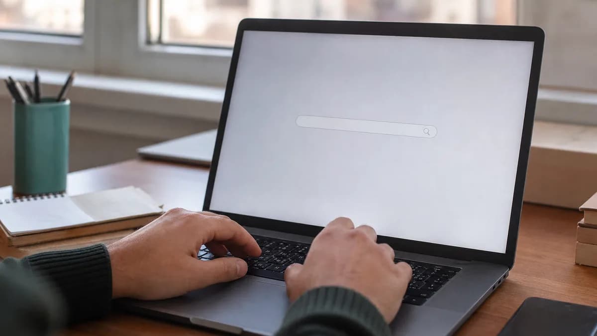 Persoon typt een domeinnaam in een zoekbalk op een laptop om beschikbaarheid te checken